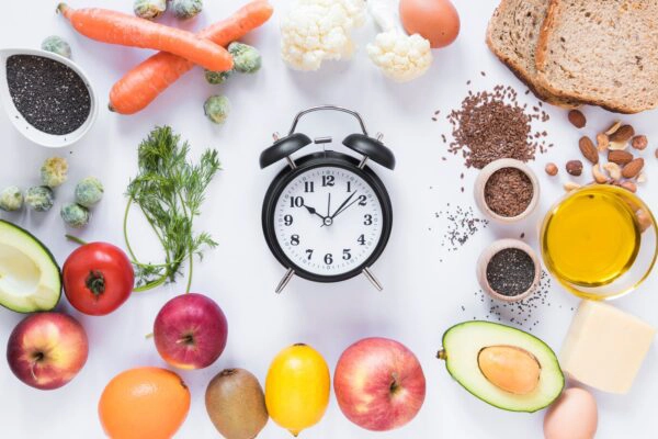 clock surrounded by various healthy foods, including fruits