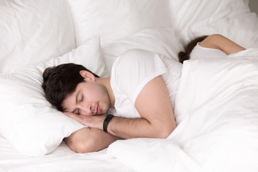 person sleeping on a bed, nestled among fluffy white pillows