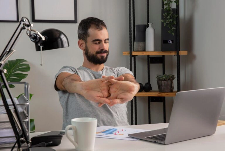Man stretching his arms while working on laptop
